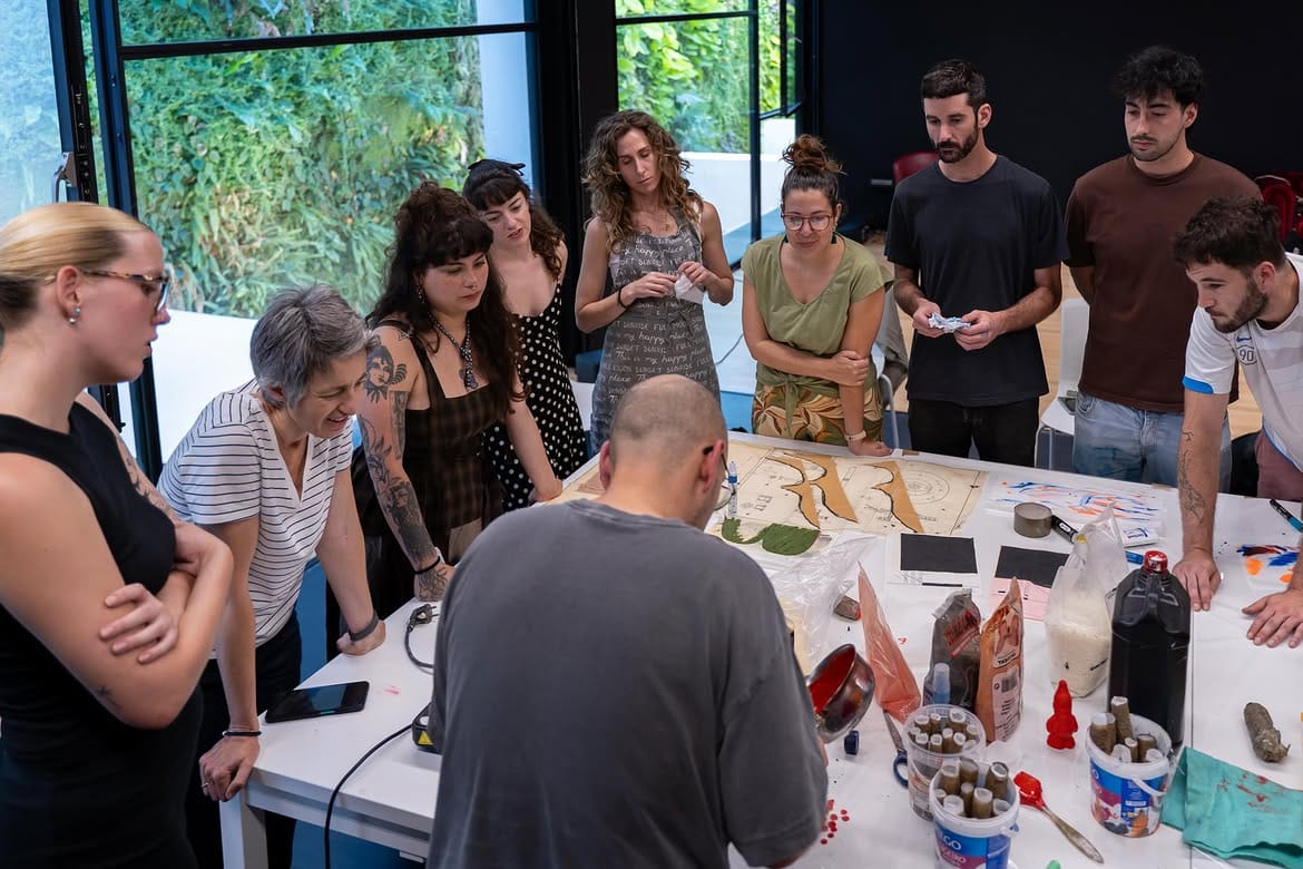 Artistas y público reunidxs alrededor de una mesa de trabajo en Atropar.